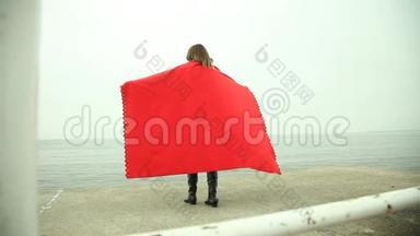 穿着红毯子的沉思的女人望着大海